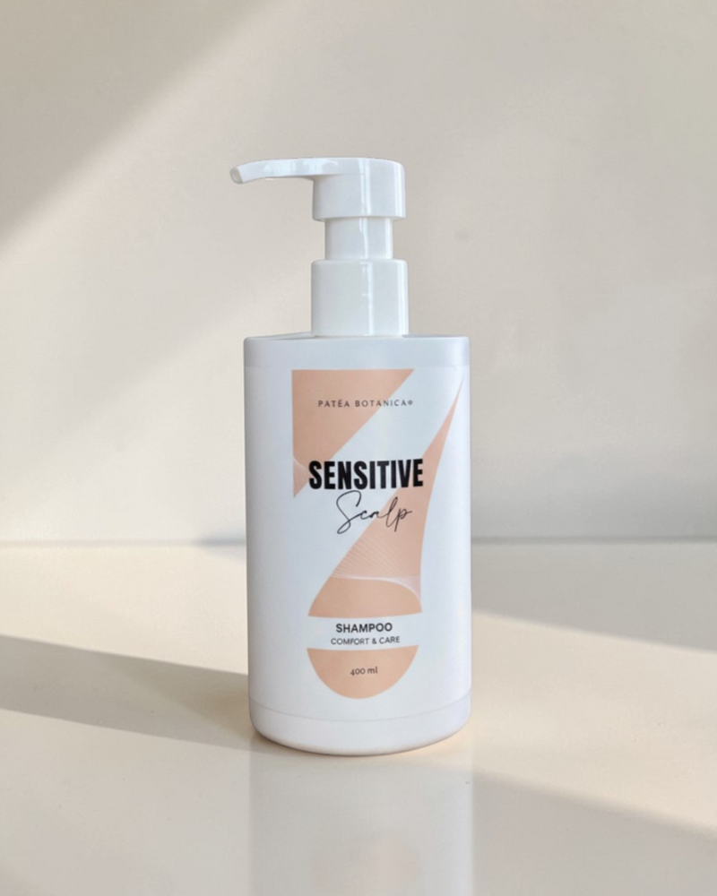 Sensitive scalp shampoo bottle on a reflective surface with a neutral background